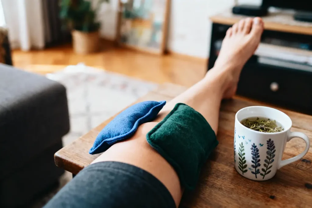 Jambe avec coussins, tasse de thé sur table en bois dans un salon confortable.
