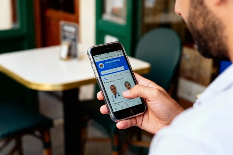 Homme utilisant un smartphone pour naviguer sur un site médical avec des portraits de médecins, en extérieur.