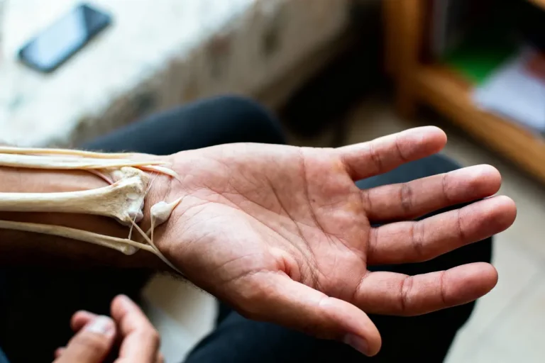 Main tendue montrant les os et tendons du bras en surimposition, téléphone en arrière-plan flou.