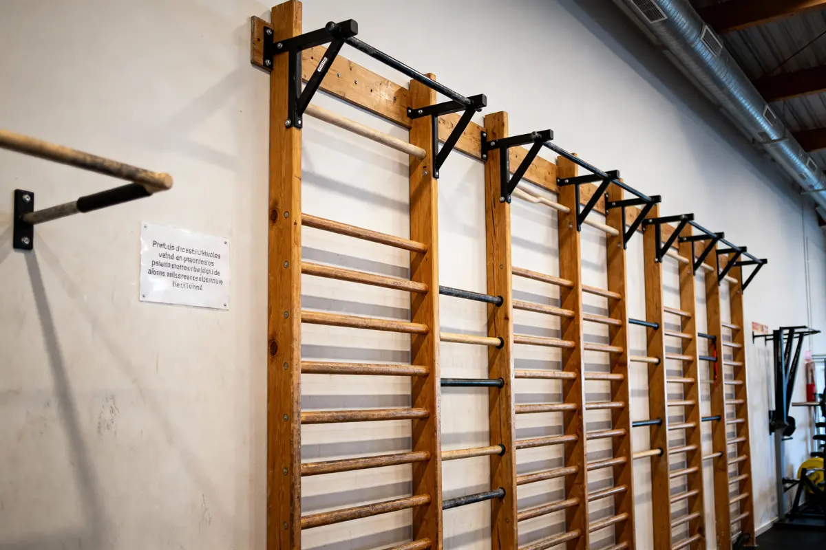 Échelles murales en bois avec des barres fixées, utilisées pour l'exercice physique, dans une salle de sport.