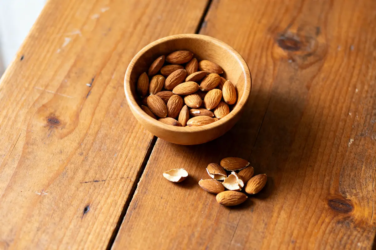 Bol d'amandes sur table en bois soulignant le danger de manger trop d'amandes