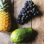 Ananas, papaye et raisins sur une table en bois les 3 fruits à éviter pendant la grossesse