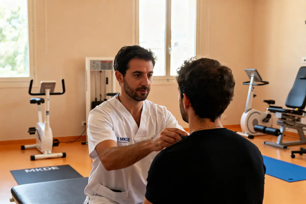 Praticien en blouse MKDE examine la posture d'un patient dans une salle de rééducation