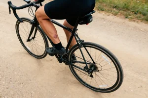 Cycliste sur chemin de terre avec kyste poplité visible sur le mollet gauche