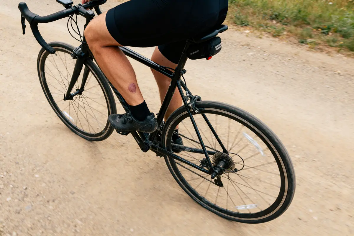 Cycliste sur chemin de terre avec kyste poplité visible sur le mollet gauche
