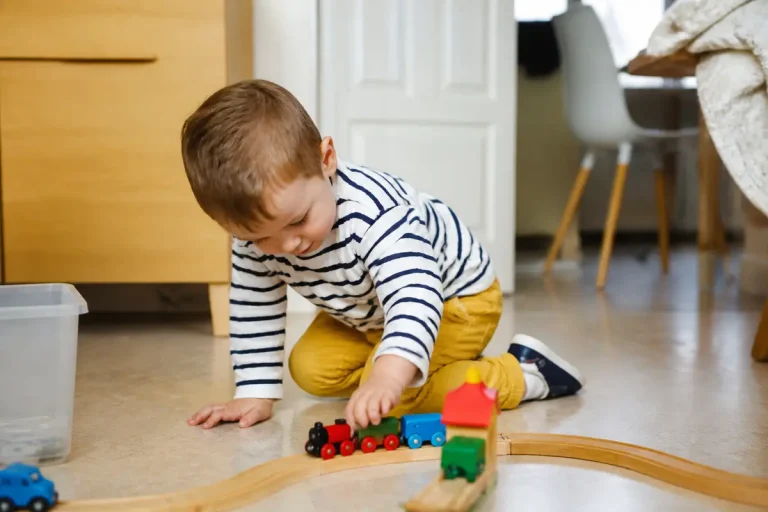 Jeune enfant jouant avec train miniature reflétant la taille d'un enfant de 3 ans
