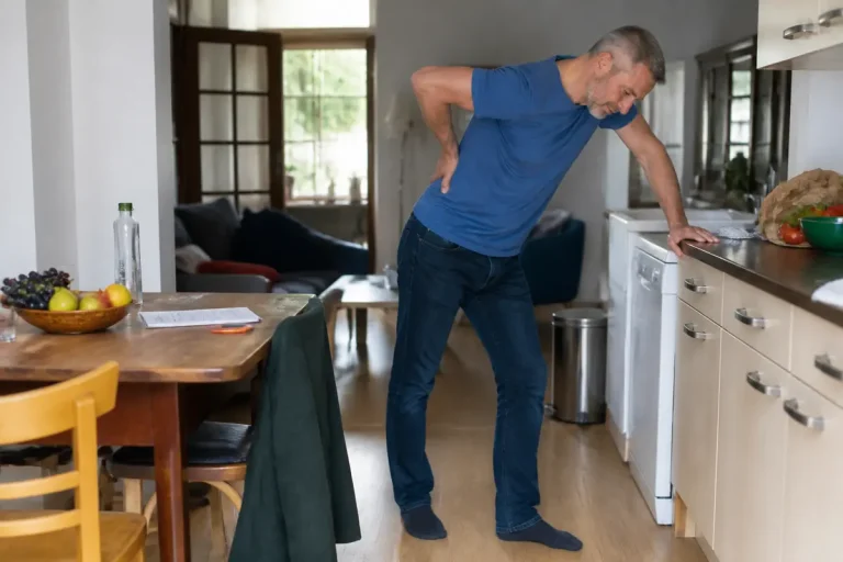 Homme souffrant dans la cuisine, illustrant vivre avec une hernie foraminale douloureuse.